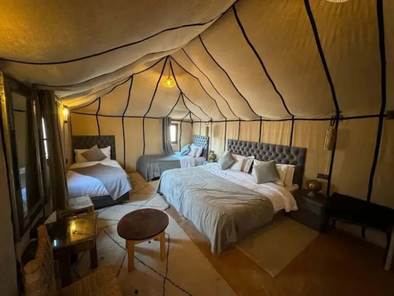 Habitación familiar en tienda en Merzouga Eastern Camp Luxury en Merzouga con una cama king, una cama individual y zona de estar.