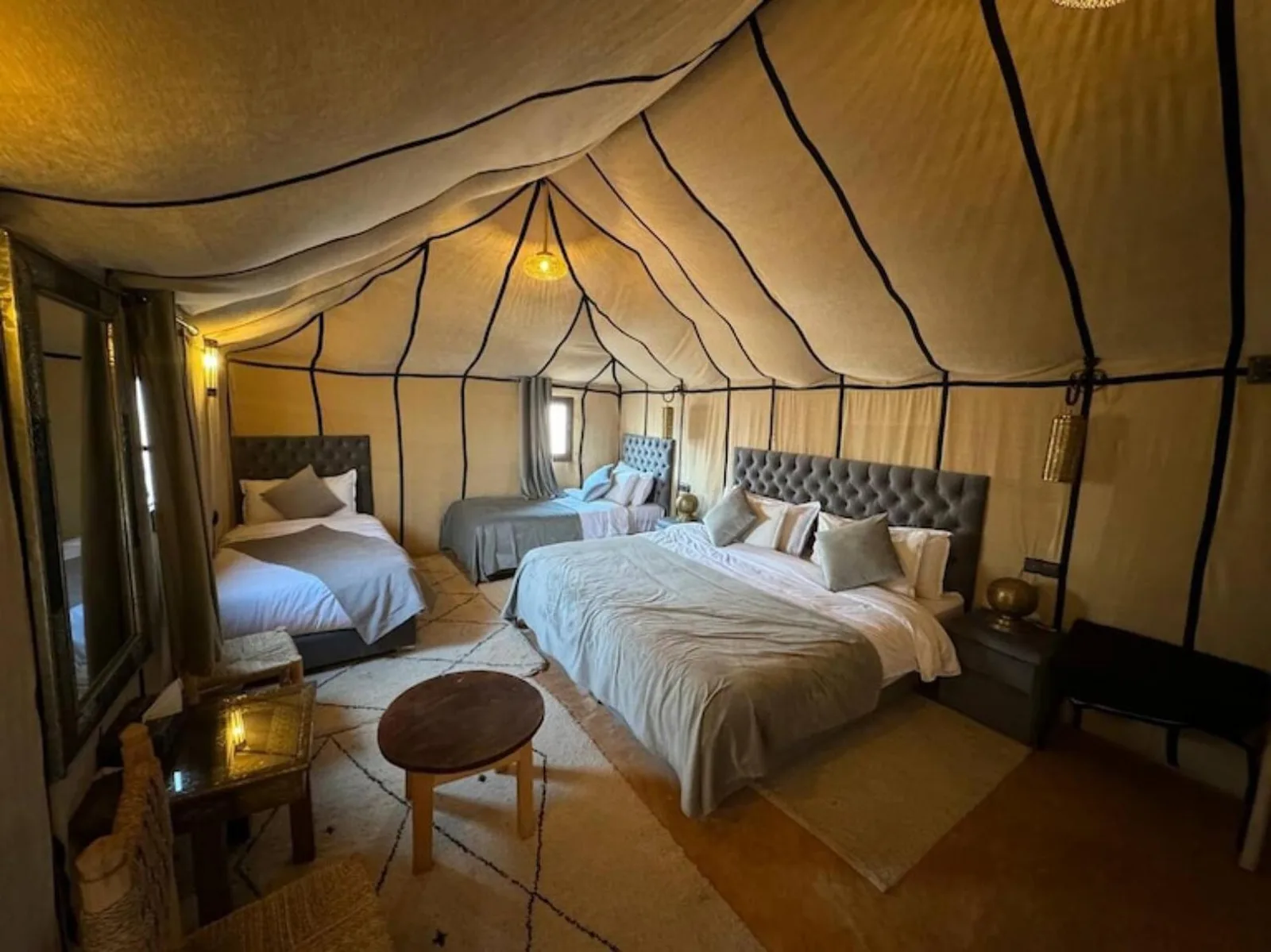 Habitación familiar en tienda en Merzouga Eastern Camp Luxury en Merzouga con una cama king, una cama individual y zona de estar.