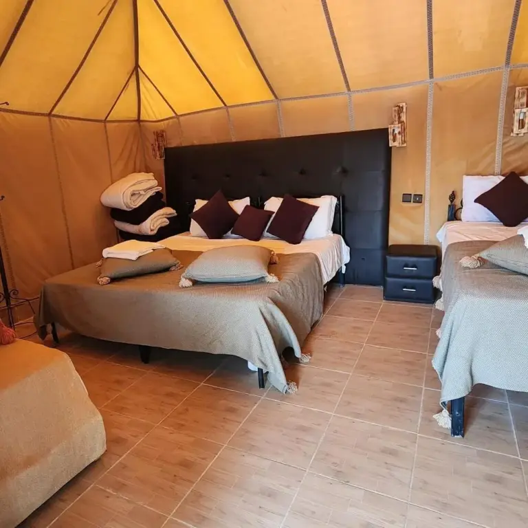 Quad tent room at Merzouga Golden Dunes Luxury Camp in Merzouga with multiple beds and warm neutral bedding.