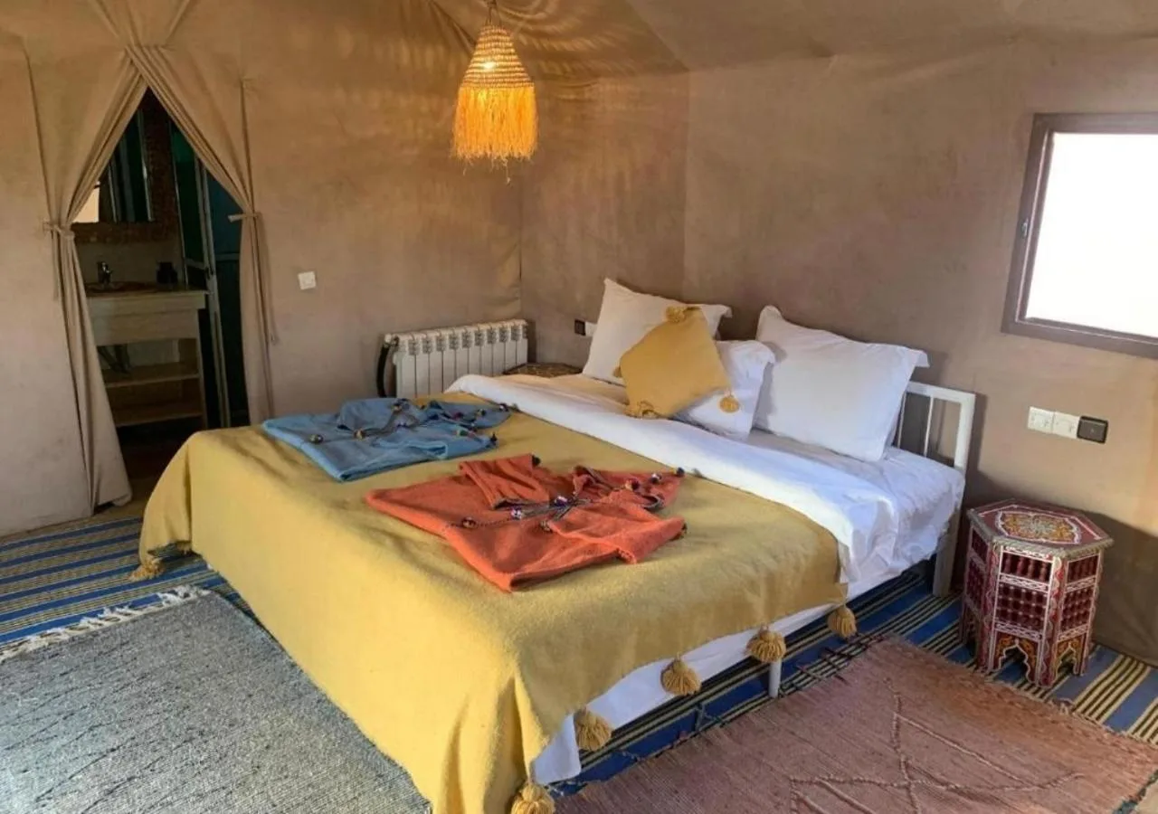 Doppelzimmer im Merzouga Legacy Camp in Merzouga mit farbenfroher Bettwäsche und hellem Zeltinterieur