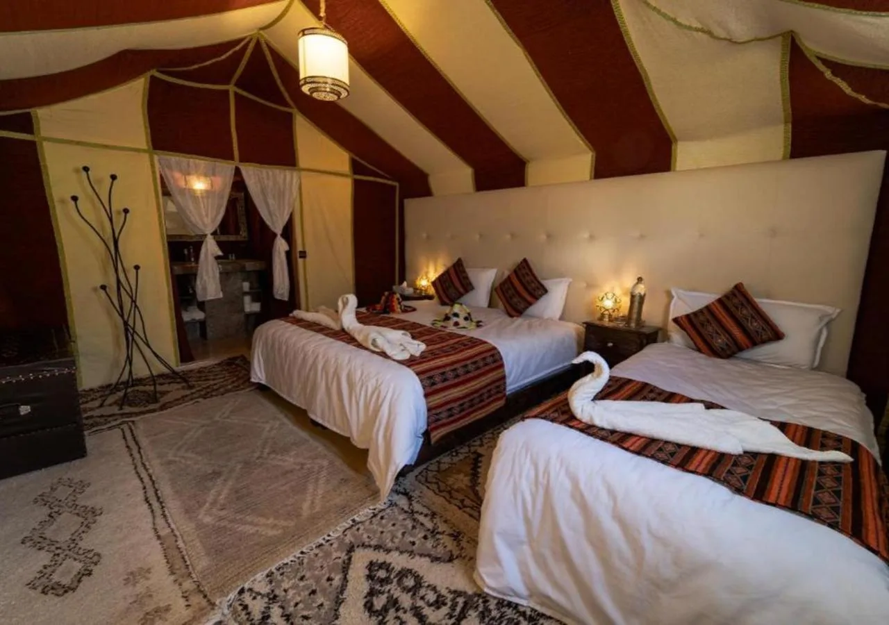 Dreibett-Zeltzimmer im Merzouga Legacy Camp in Merzouga mit drei Betten und warmer marokkanischer Einrichtung