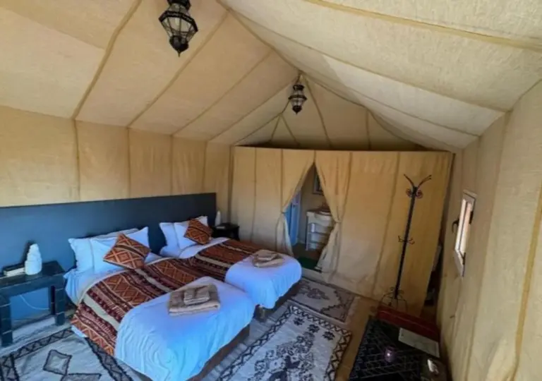 Zweibett-Zeltsuite im Merzouga Legacy Camp in Merzouga mit gemusterten Teppichen und eleganten Leinwandwänden