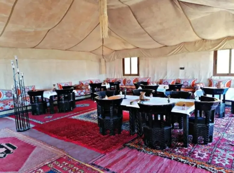 Dining tent interior at Merzouga Luxe Camp in Merzouga with carpeted seating and tables