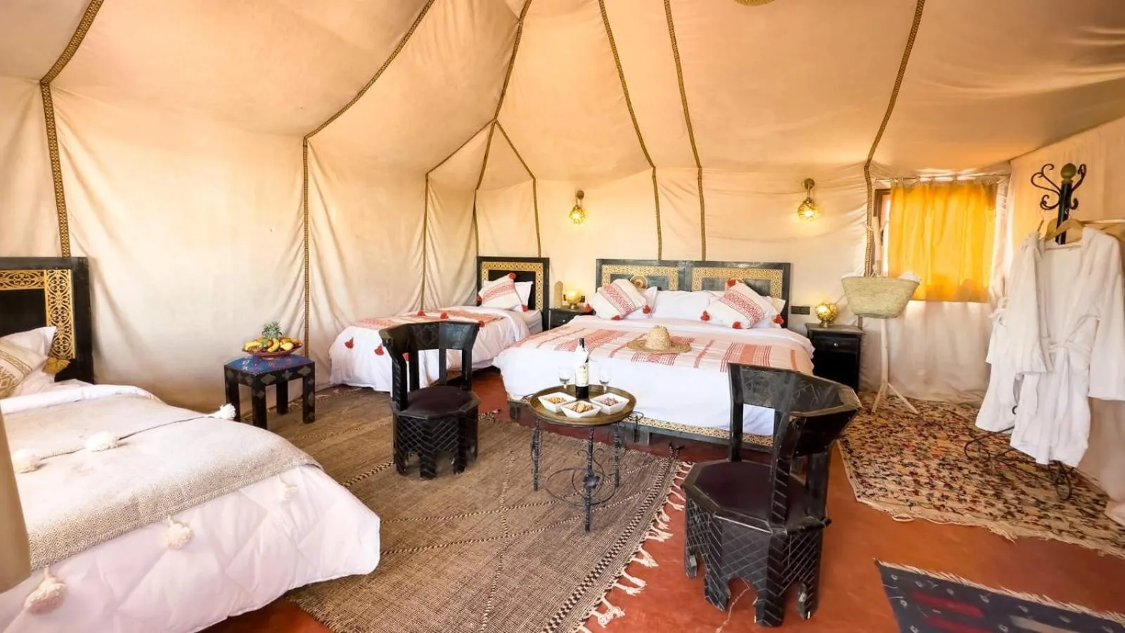 Spacious luxury tent room at Merzouga Luxe Camp in Merzouga with multiple beds and Moroccan decor