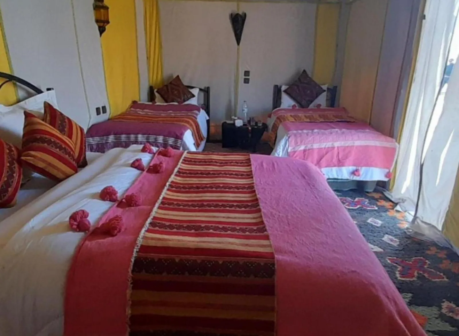 Habitación tienda familiar de Merzouga Luxurious Camp con varias camas y ropa de cama a rayas en Merzouga, Marruecos