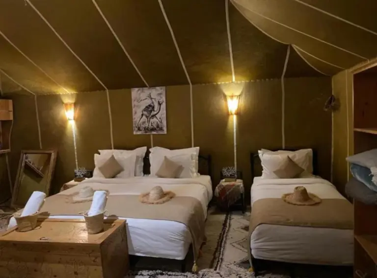 Twin bedroom interior at Merzouga Retreat Camp in Merzouga with two beds, lamps, and desert-style decor.