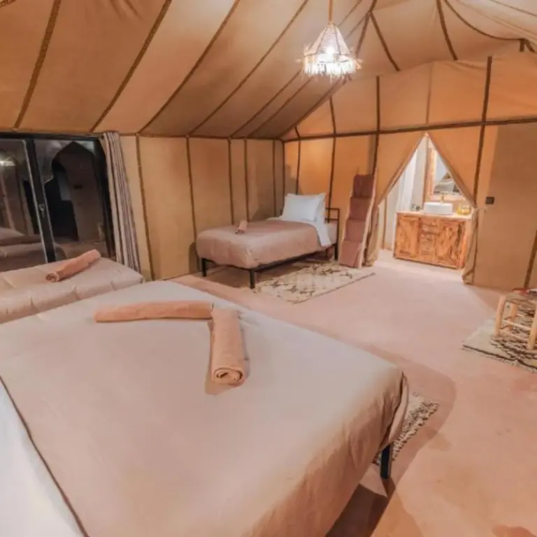 Interior de una amplia suite tienda en Merzouga Royal Camp en Merzouga con varias camas y una zona de estar