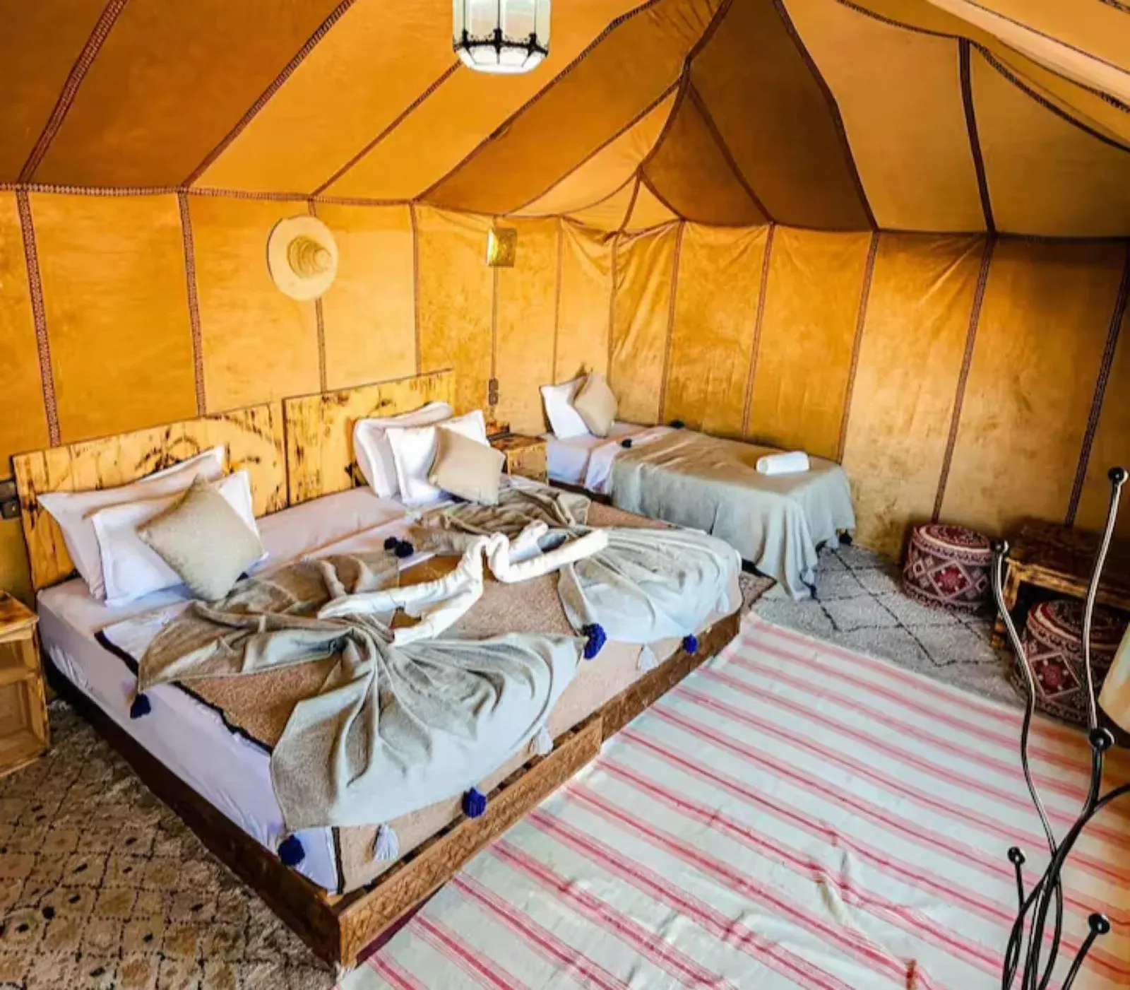 Großes Zeltzimmer im Merzouga Sahara Top Camp in Merzouga mit mehreren Betten und warmen kamelfarbenen Wänden