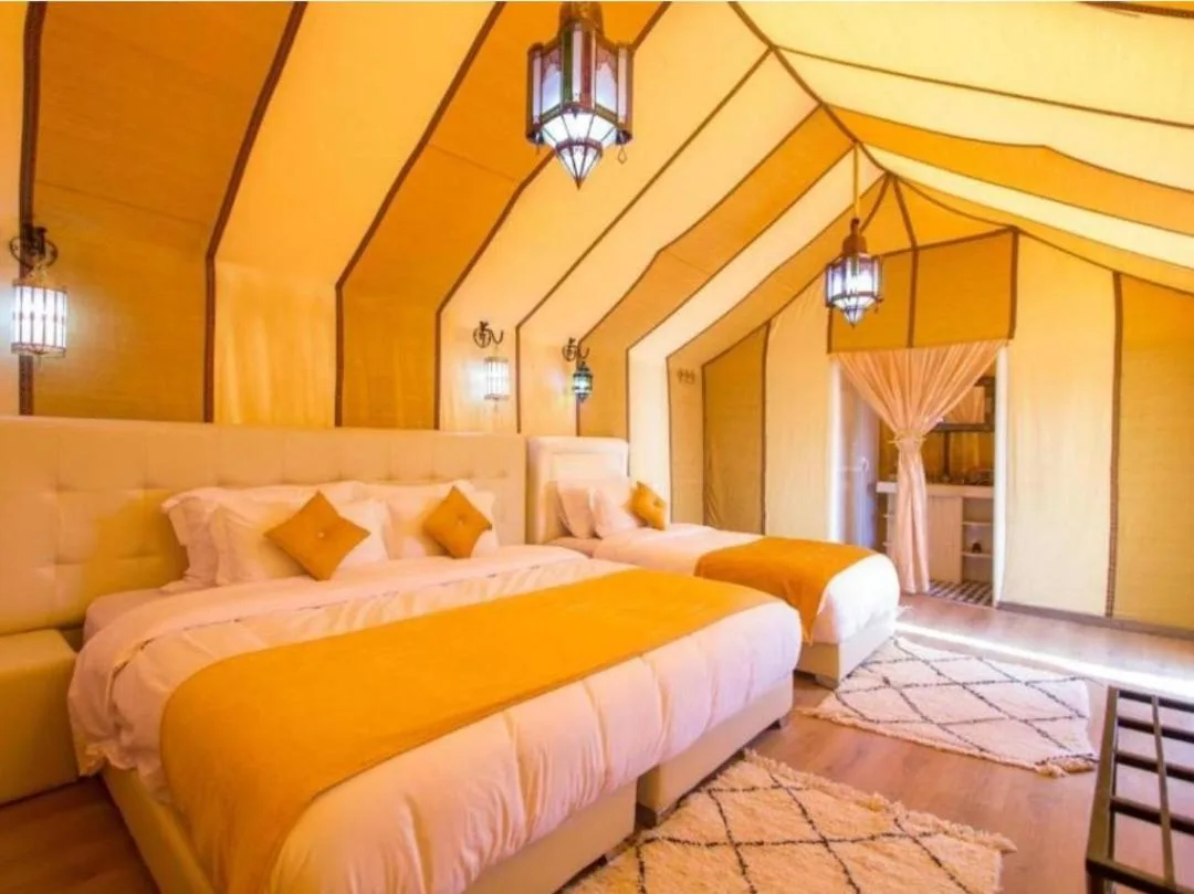 Deluxe-Zeltzimmer im Merzouga Sara Luxury Camp in Merzouga mit gelben Vorhängen und zwei Betten