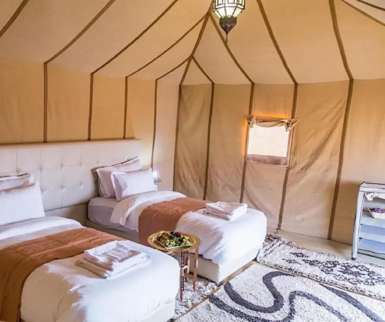 Geräumiges Familienzelt im Merzouga Sara Luxury Camp in Merzouga mit zwei Betten und gemusterten Teppichen