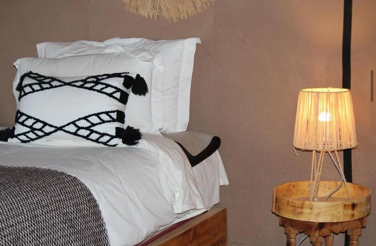 Einzelbett in einem Zelt im Merzouga Sara Luxury Camp in Merzouga mit dekorativem Kissen und Nachttischlampe