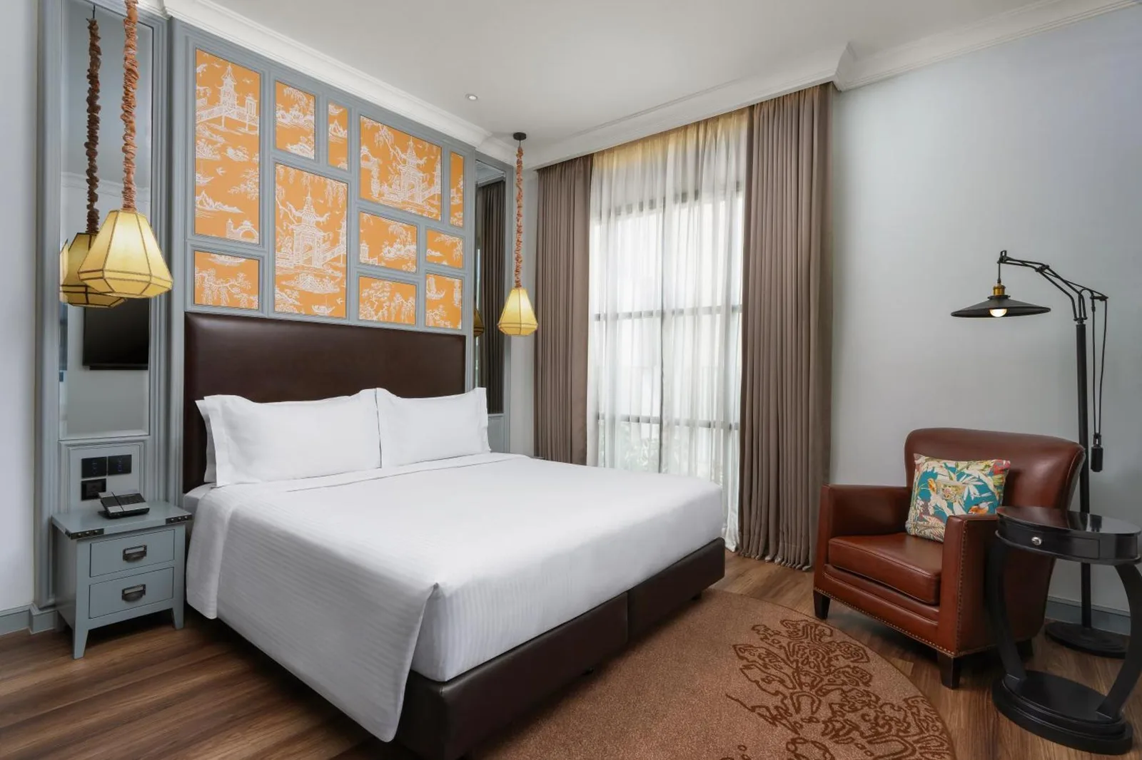 Habitación luminosa en Metropole, Bangkok, a Tribute Portfolio Hotel con una cama king, sillón de cuero y ventana de suelo a techo.