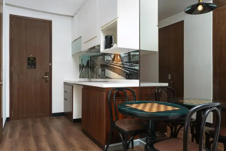 Rincón de cocina y comedor en Metropole, Bangkok, a Tribute Portfolio Hotel con mesa, sillas y armarios compactos.