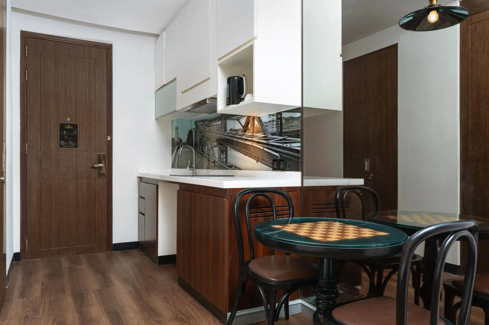 Rincón de cocina y comedor en Metropole, Bangkok, a Tribute Portfolio Hotel con mesa, sillas y armarios compactos.