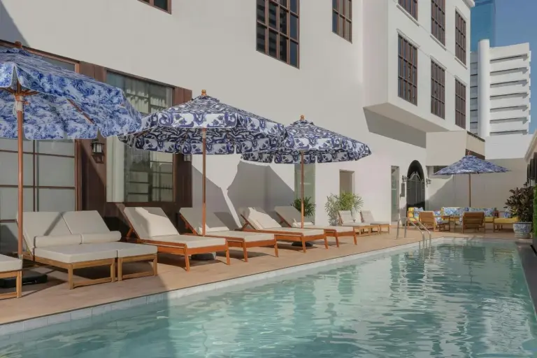 Terraza de la piscina al aire libre en Metropole, Bangkok, a Tribute Portfolio Hotel en Bangkok, con tumbonas y sombrillas estampadas.