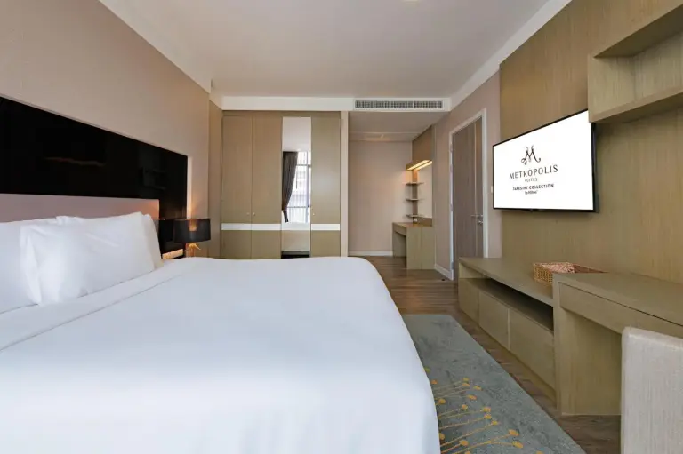 Compact bedroom corner at Metropolis Suites Bangkok, Tapestry Collection by Hilton with bed, TV, and storage