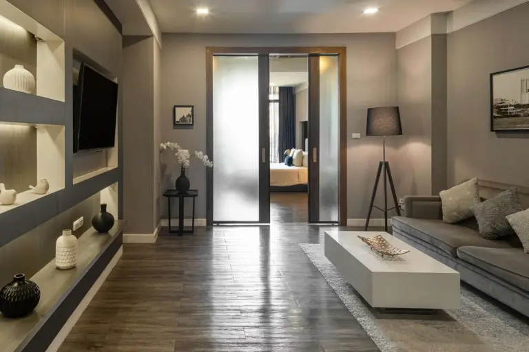 Modern suite living area at Metropolis Suites Bangkok, Tapestry Collection by Hilton with built-in shelving and sofa seating