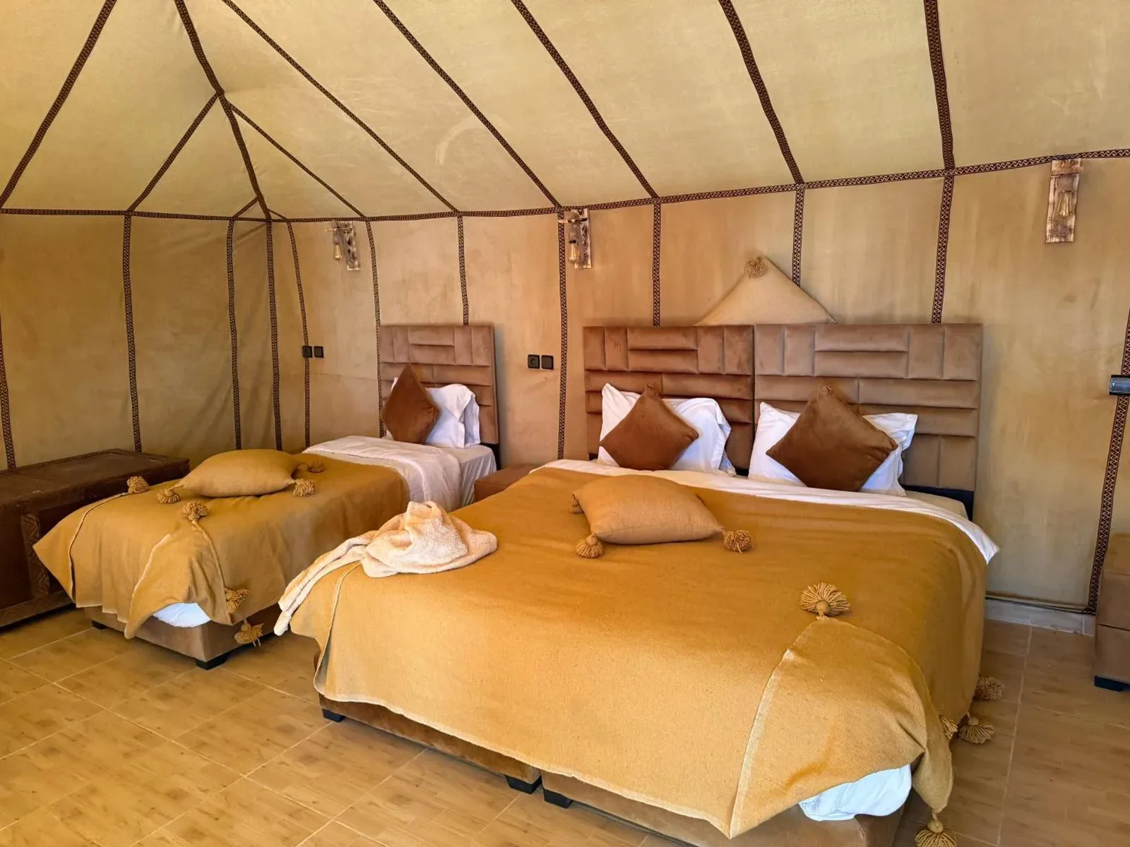 Milagro Luxury Camps in Merzouga family tent room with three beds and desert-style bedding