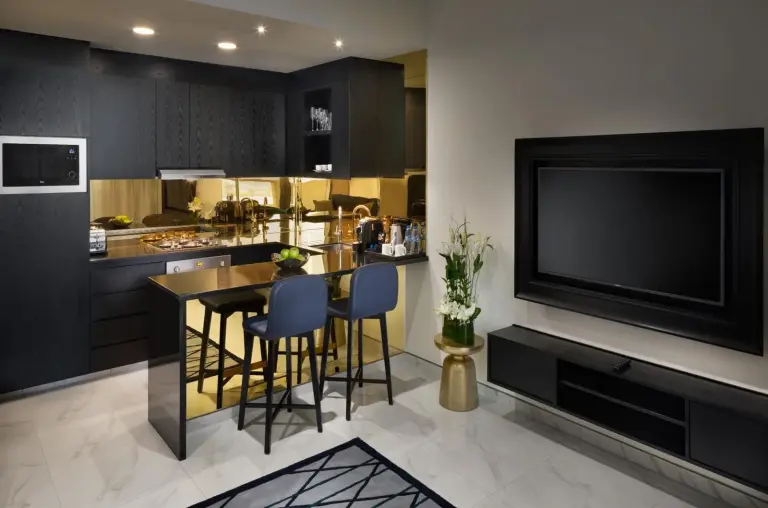 Millennium Atria Business Bay – Dubai, United Arab Emirates hotel – a kitchen with a bar with chairs and a flat screen tv at Millennium Atria Business Bay in Dubai