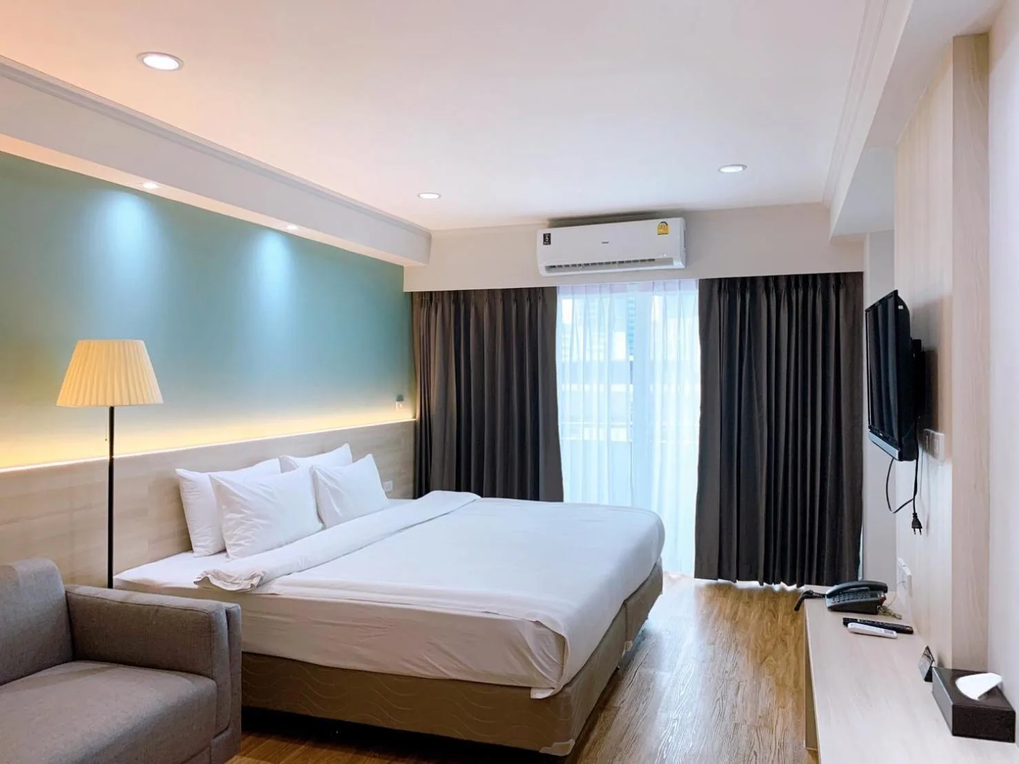 Modern king room at Miloft Sathorn Hotel in Bangkok with bed, seating area, and city view window