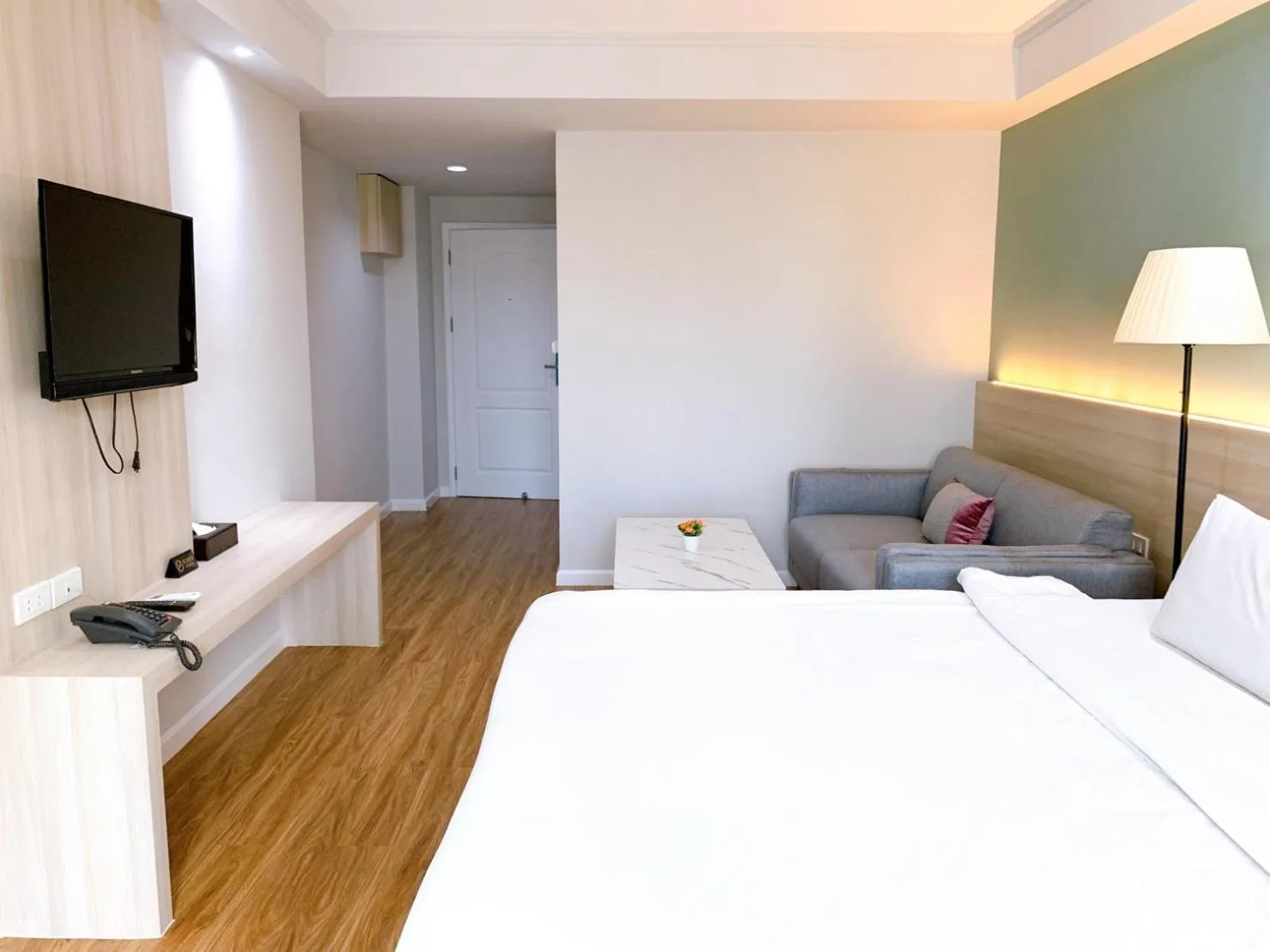 Spacious room interior at Miloft Sathorn Hotel in Bangkok with TV, bed, and sofa seating