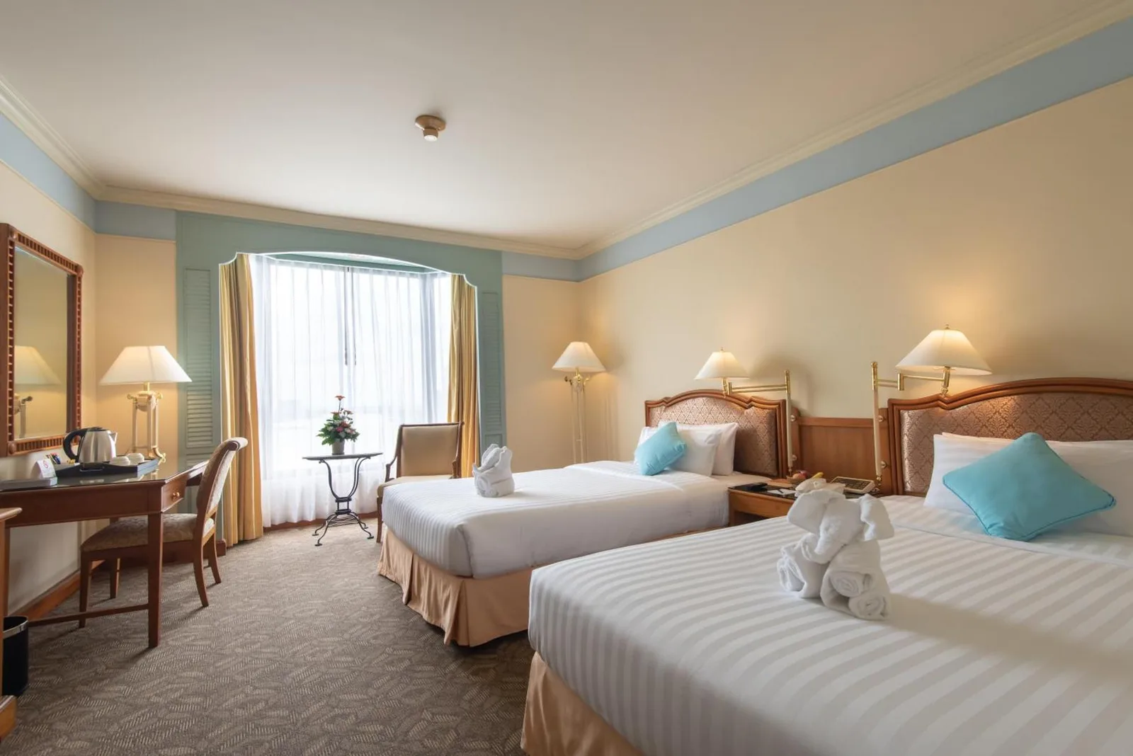 Twin guest room at Montien Riverside Hotel Bangkok with two single beds, desk, and window seating area.