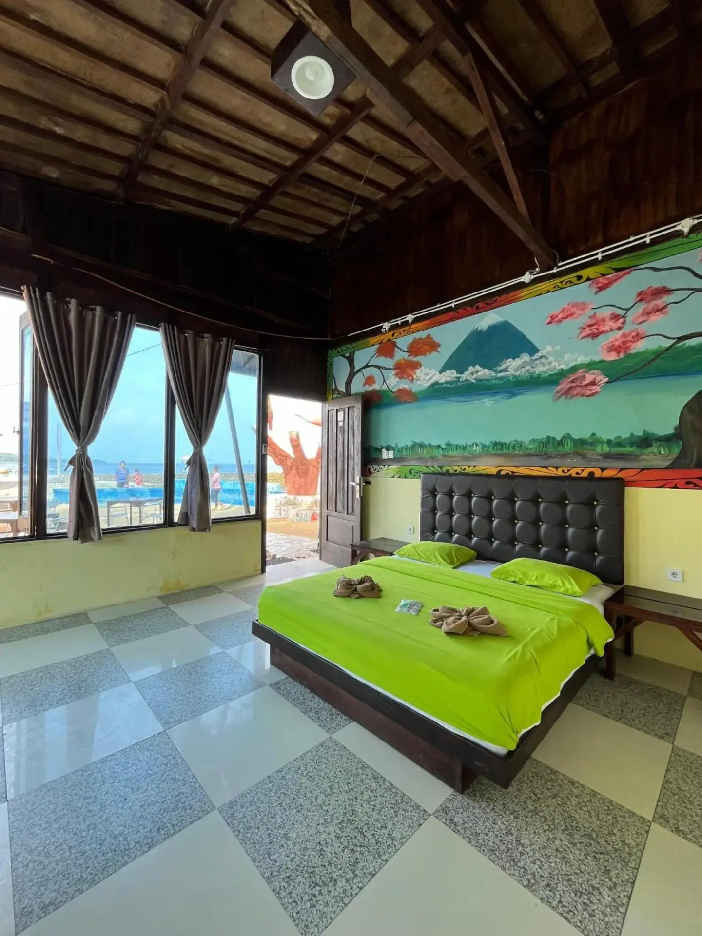 Deluxe room at Mooi Park in Sorong with patterned floor tiles, mural wall art, and a large bed.