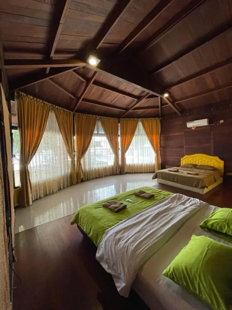 Ocean view room at Mooi Park in Sorong with twin beds, wooden interior, and large windows with curtains.
