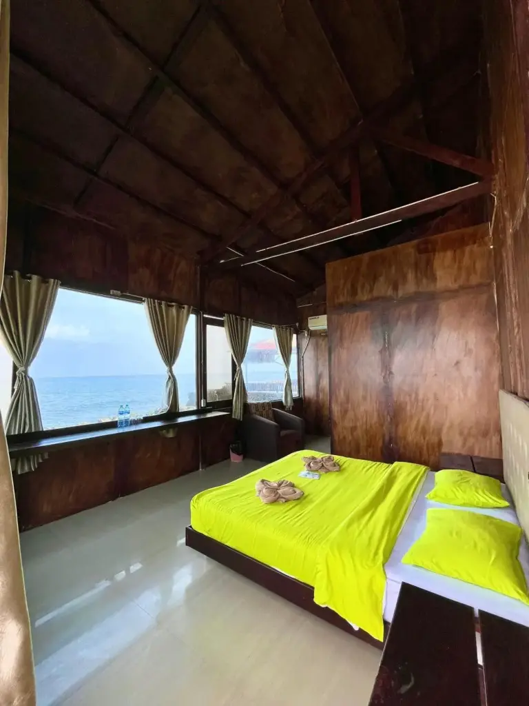 Sea view room at Mooi Park in Sorong with a bright bed, wood interior, and windows facing the ocean.