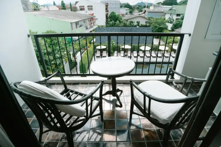 Balcony seating at MORA Boutique Hotel Chiang Rai with table, chairs, and pool view