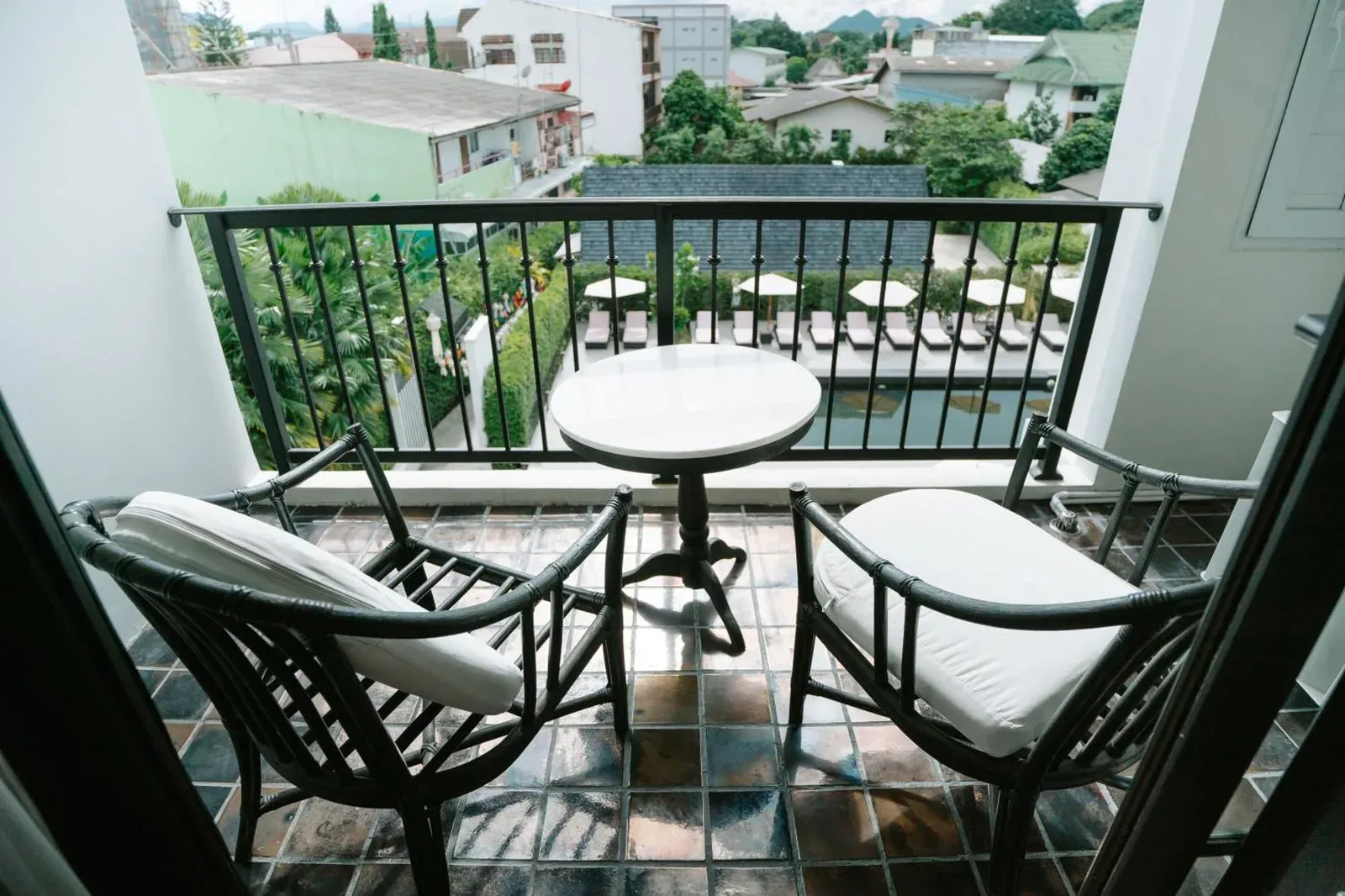 Balcony seating at MORA Boutique Hotel Chiang Rai with table, chairs, and pool view