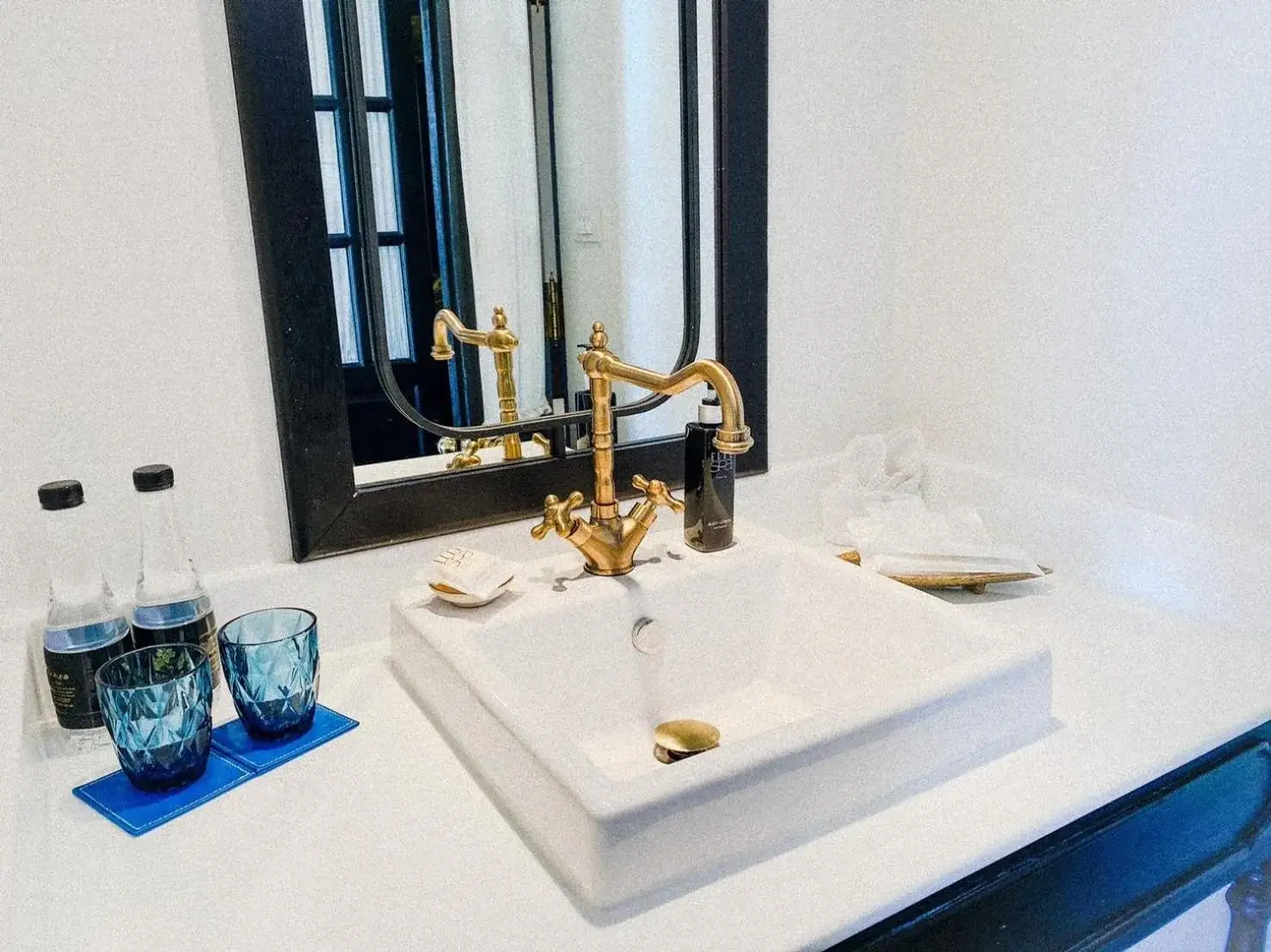 Bathroom sink and mirror at MORA Boutique Hotel Chiang Rai with gold fixtures and toiletries