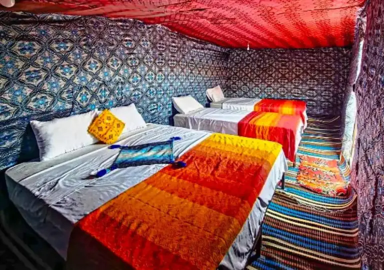 Moroccan Desert Camp in Merzouga tent bedroom with twin beds, colorful blankets, and patterned desert decor