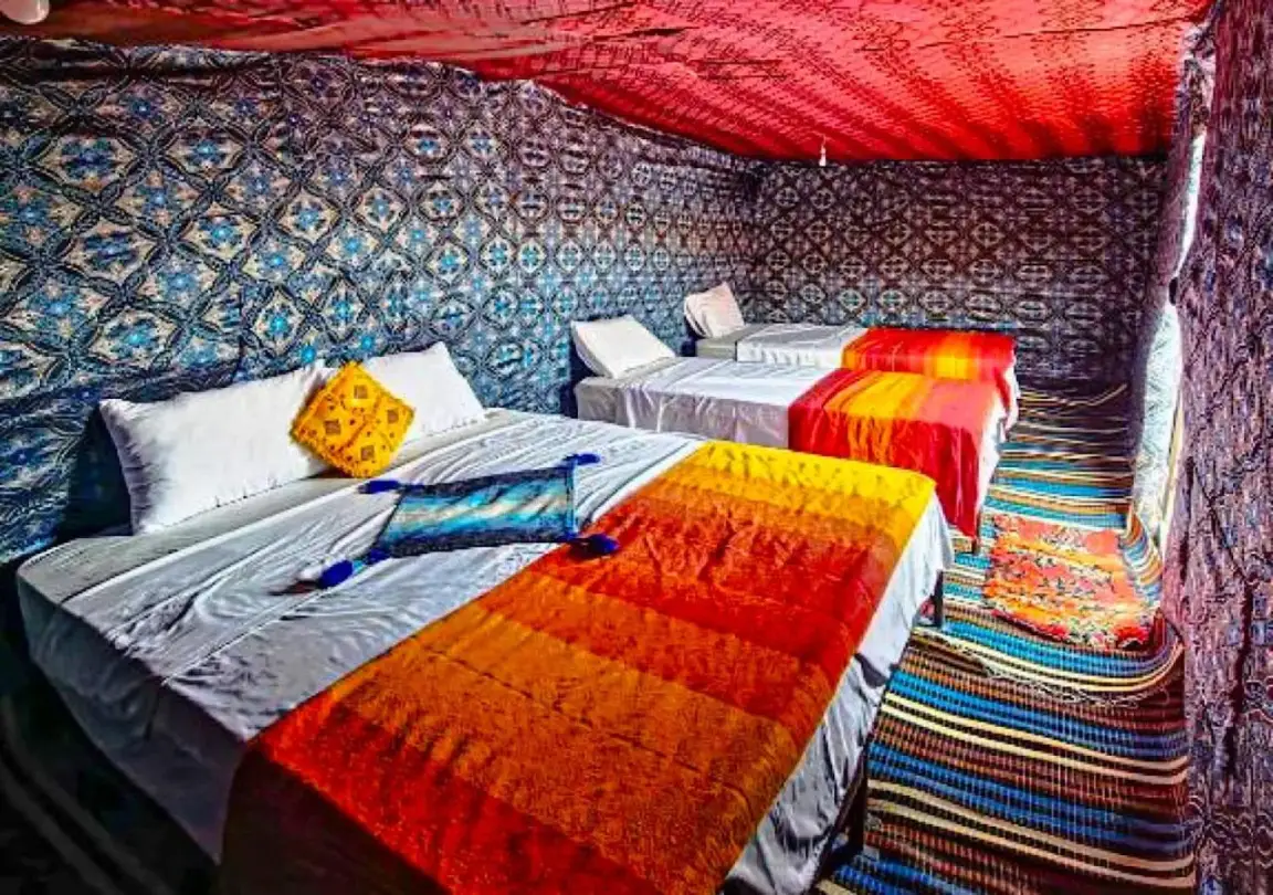 Moroccan Desert Camp in Merzouga tent bedroom with twin beds, colorful blankets, and patterned desert decor