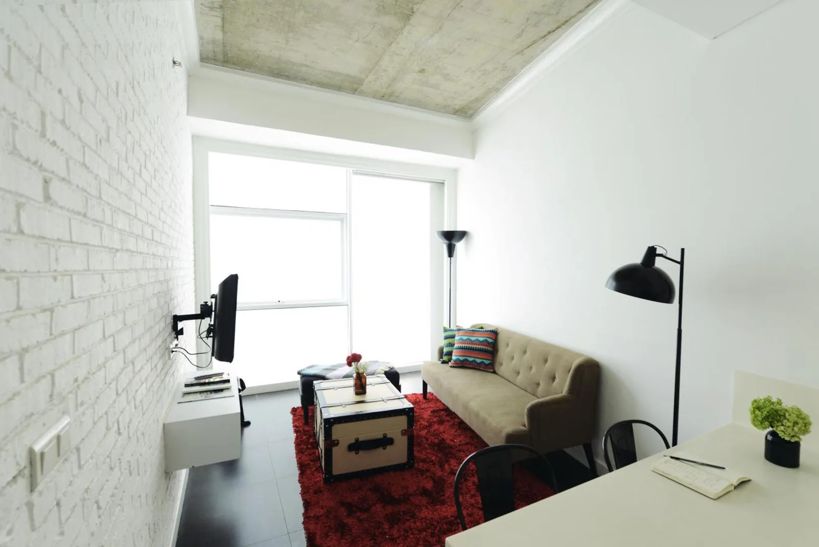 Wohnzimmer im Morrissey Hotel Jakarta mit Sofa, Teppich, Couchtisch und Arbeitsbereich.