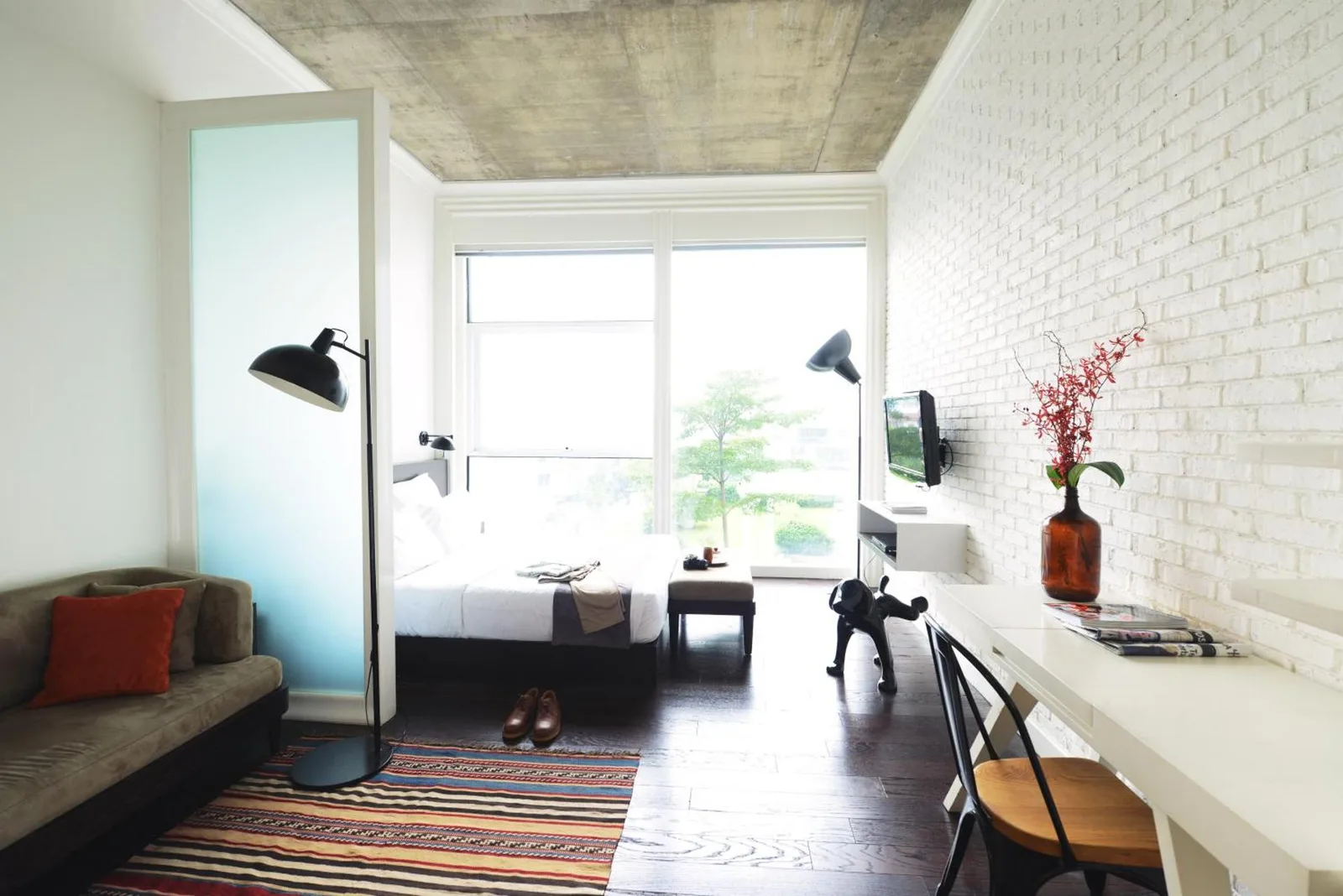 Studio-Suite im Morrissey Hotel Jakarta mit Sitzbereich, Bett, Schreibtisch und modernem Loft-Design.