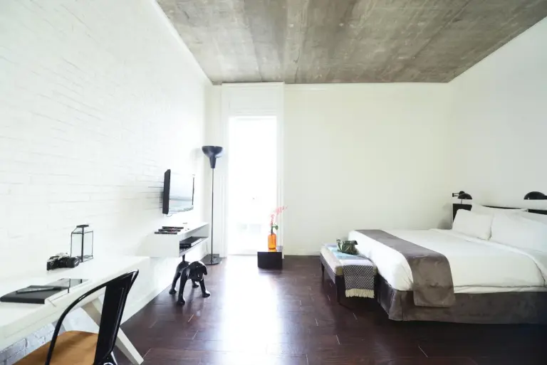 Geräumiges Suite-Interieur im Morrissey Hotel Jakarta mit Bett, Schreibtisch und großem Fenster.