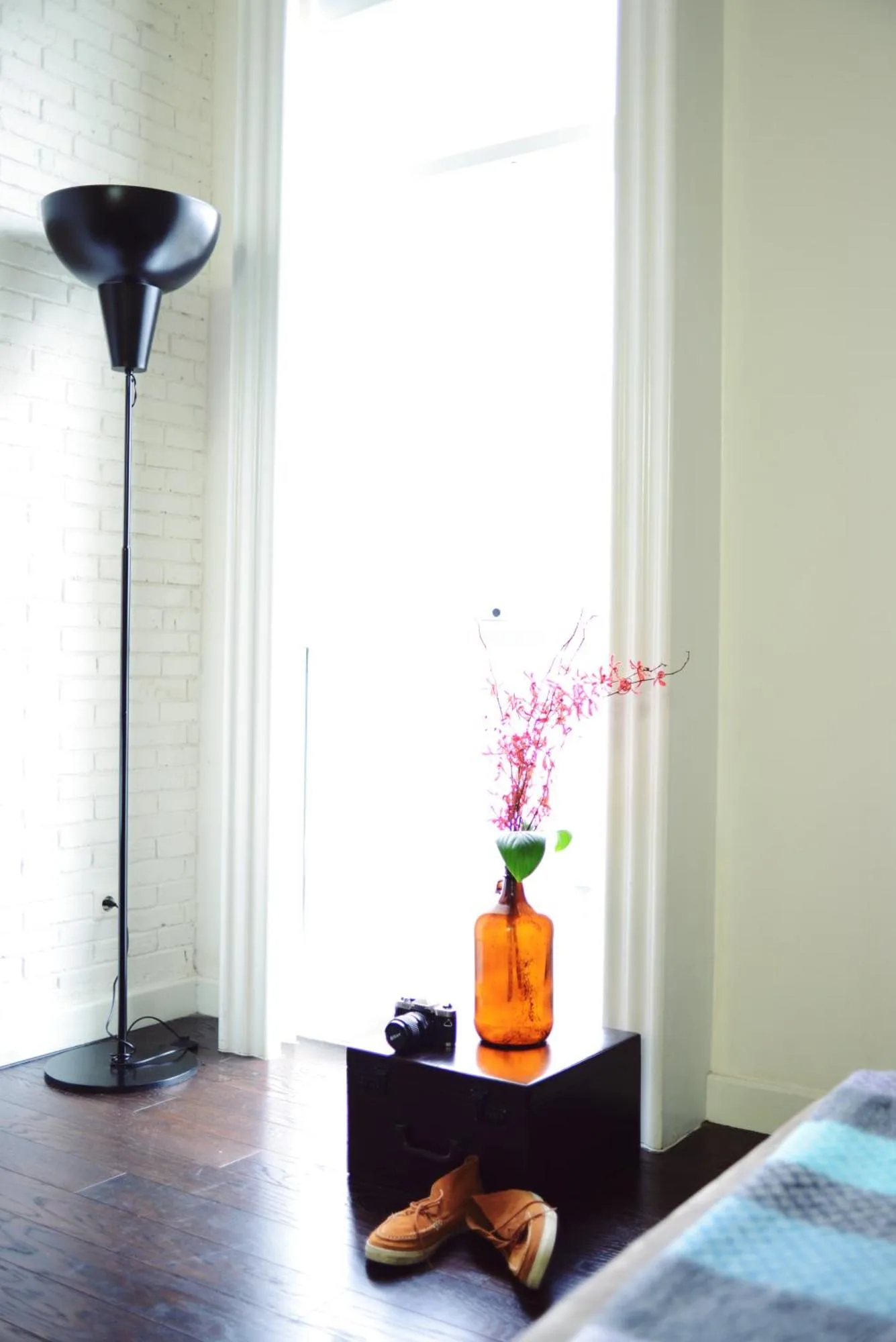 Helle Fensterecke im Morrissey Hotel Jakarta mit Stehlampe, Vase und Details am Bett.