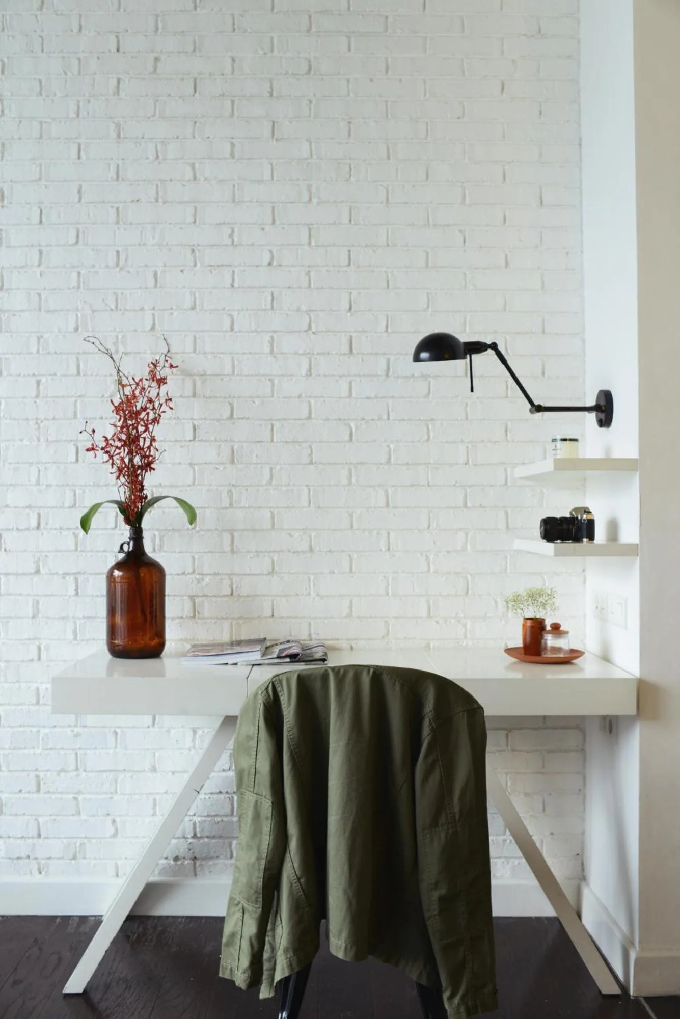 Minimalistischer Schreibtisch im Morrissey Hotel Jakarta mit Lampe, Stuhl und dekorativer Vase.