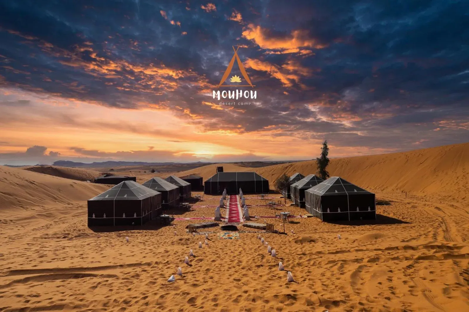 Mouhou Desert Camp en Merzouga con tiendas de lujo entre dunas de arena al atardecer