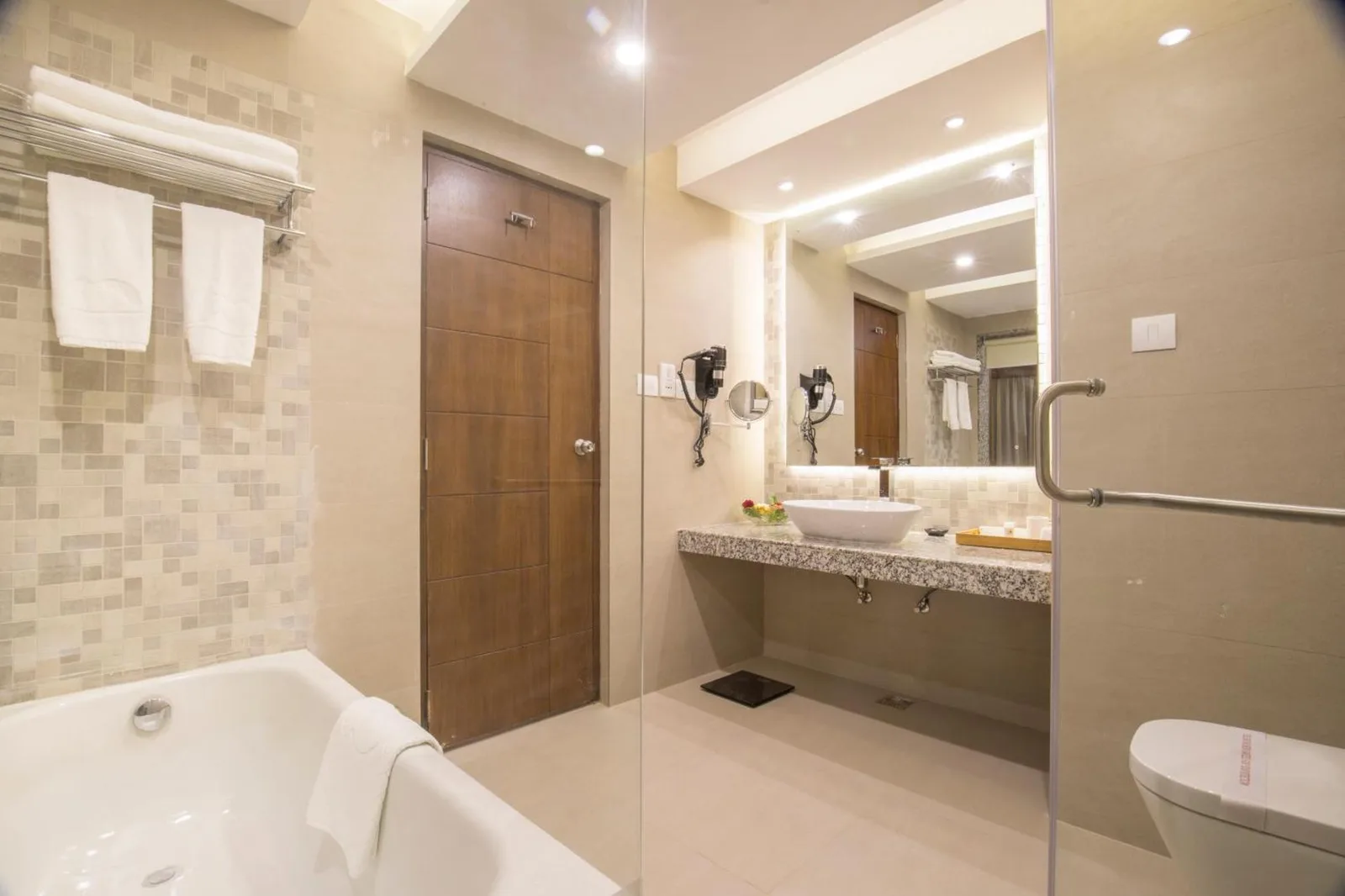 Salle de bains élégante au Mountain Glory Forest Resort and Spa, Pokhara avec baignoire, vasque et espace douche vitré.