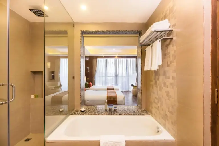 Salle de bains avec baignoire au Mountain Glory Forest Resort and Spa, Pokhara avec miroir, espace douche et murs carrelés.