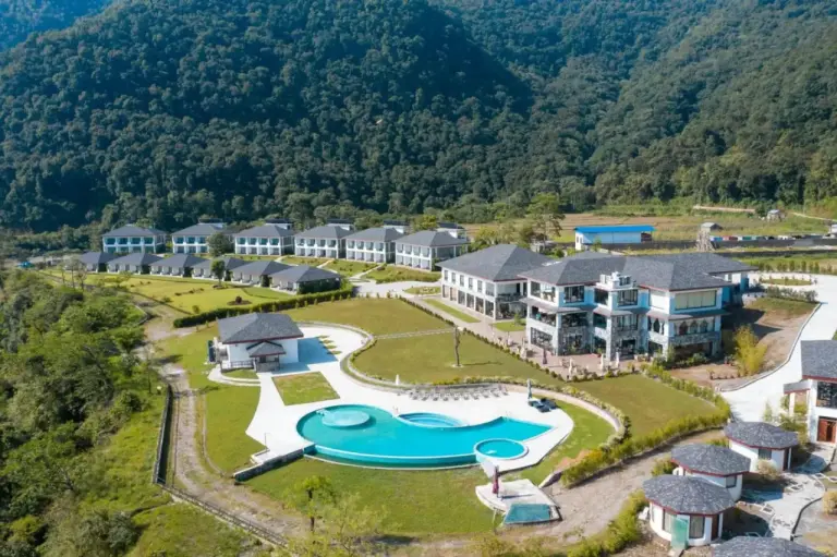 Vue aérienne de Mountain Glory Forest Resort and Spa, Pokhara avec des bâtiments à flanc de colline, une piscine et un décor de montagne à Pokhara, Nepal.