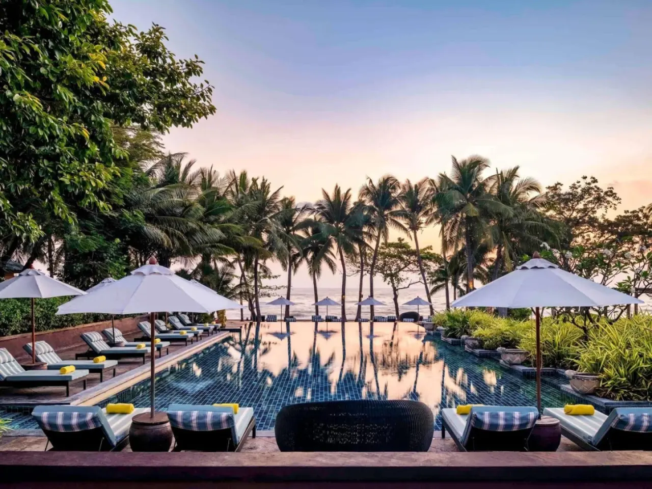 Mövenpick Asara Resort & Spa Hua Hin – Hua Hin, Thaïlande hôtel – une piscine de resort avec chaises et parasols et palmiers au Mövenpick Asara Resort & Spa Hua Hin à Hua Hin