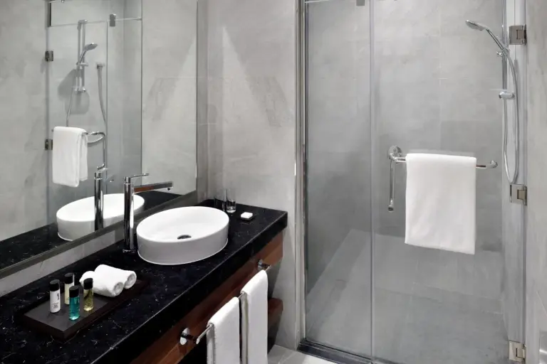 Mövenpick Hotel Apartments Downtown Dubai – hotel en Dubái, Emiratos Árabes Unidos – un baño con un lavabo y una ducha de cristal en Mövenpick Hotel Apartments Downtown Dubai en Dubái