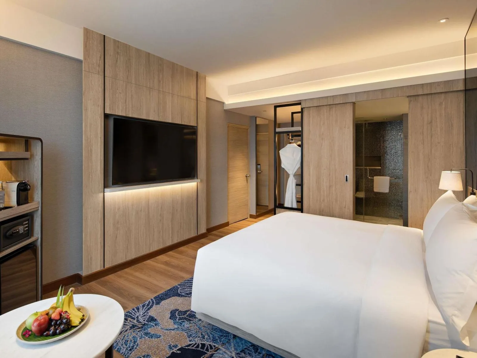 Mövenpick Hotel Jakarta City Centre – hotel de Jakarta, Indonesia – un dormitorio con una gran cama blanca y una mesa con un plato de fruta en Mövenpick Hotel Jakarta City Centre en Jakarta