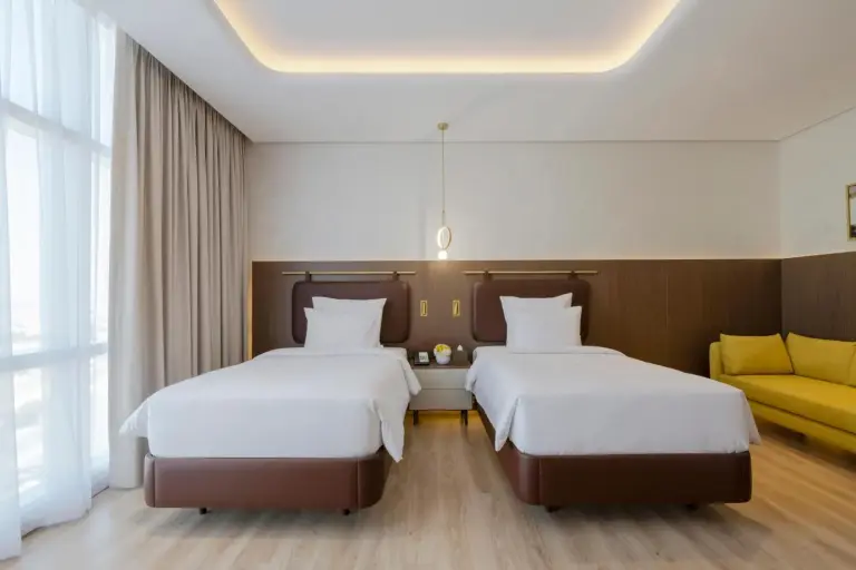Movenpick Jumeirah Village Triangle – Hotel in Dubai, Vereinigte Arabische Emirate – ein Hotelzimmer mit zwei Betten und einem Flachbildfernseher im Movenpick Jumeirah Village Triangle in Dubai
