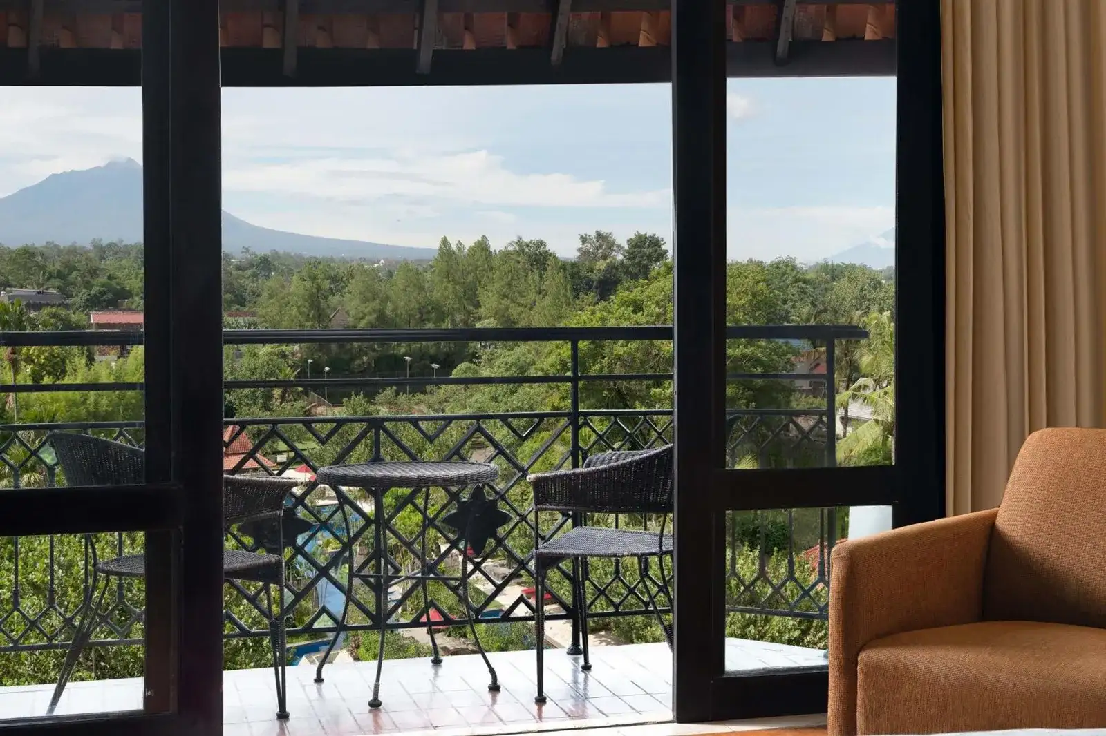 Vue depuis le balcon du Mustika Yogyakarta Resort and Spa sur la verdure et les montagnes au loin.