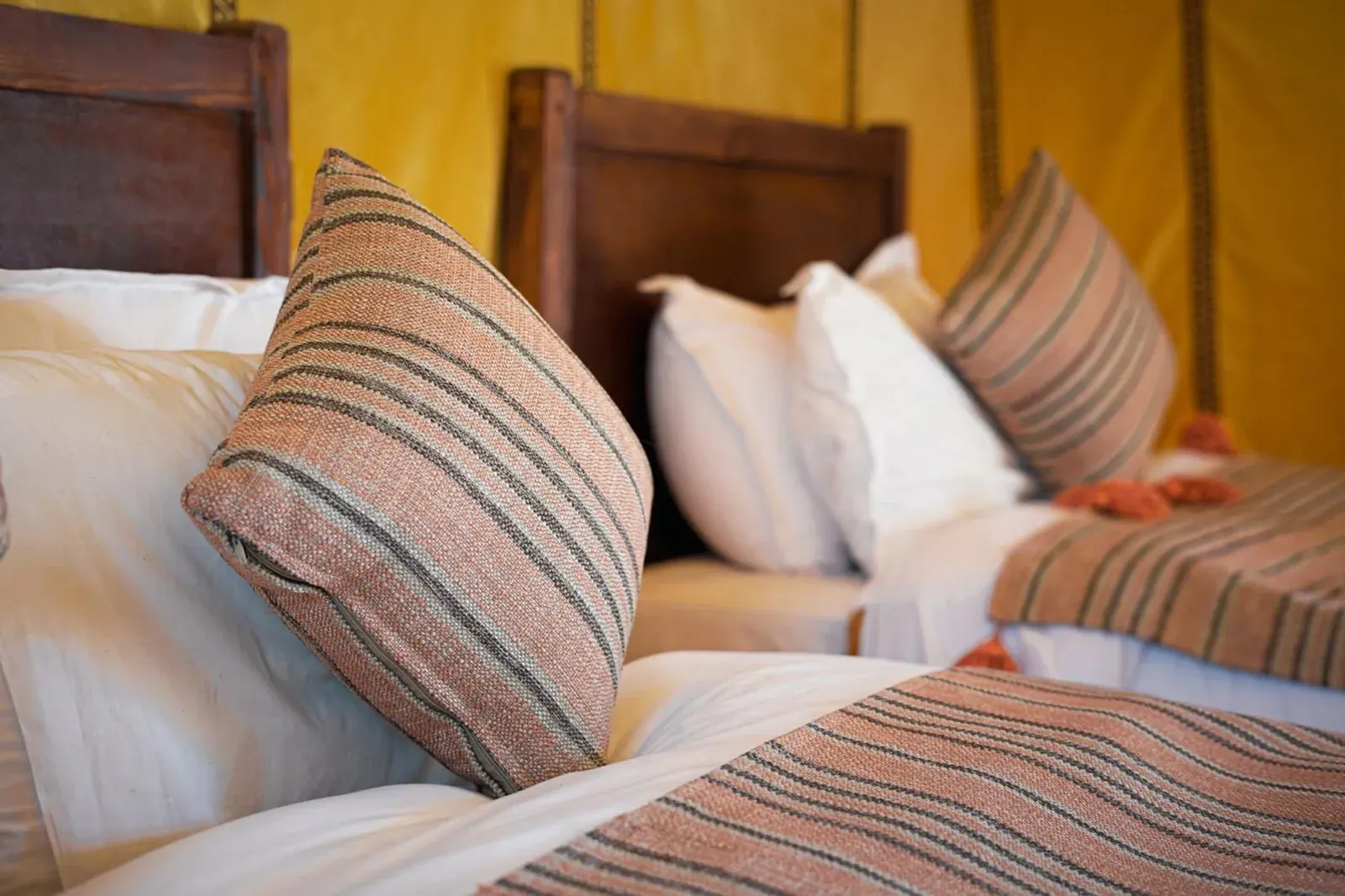 Primer plano de almohadas a rayas sobre una cama en Najma Luxury Camp en Merzouga con sábanas suaves.