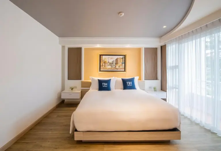 Front view of a king bed in a guest room at NH Boat Lagoon Phuket Resort in Phuket.